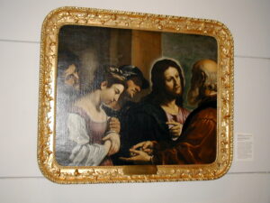 A restored painting of Christ inside a golden metal frame