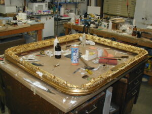 A metal picture frame with various tools for restoration inside of it on a table